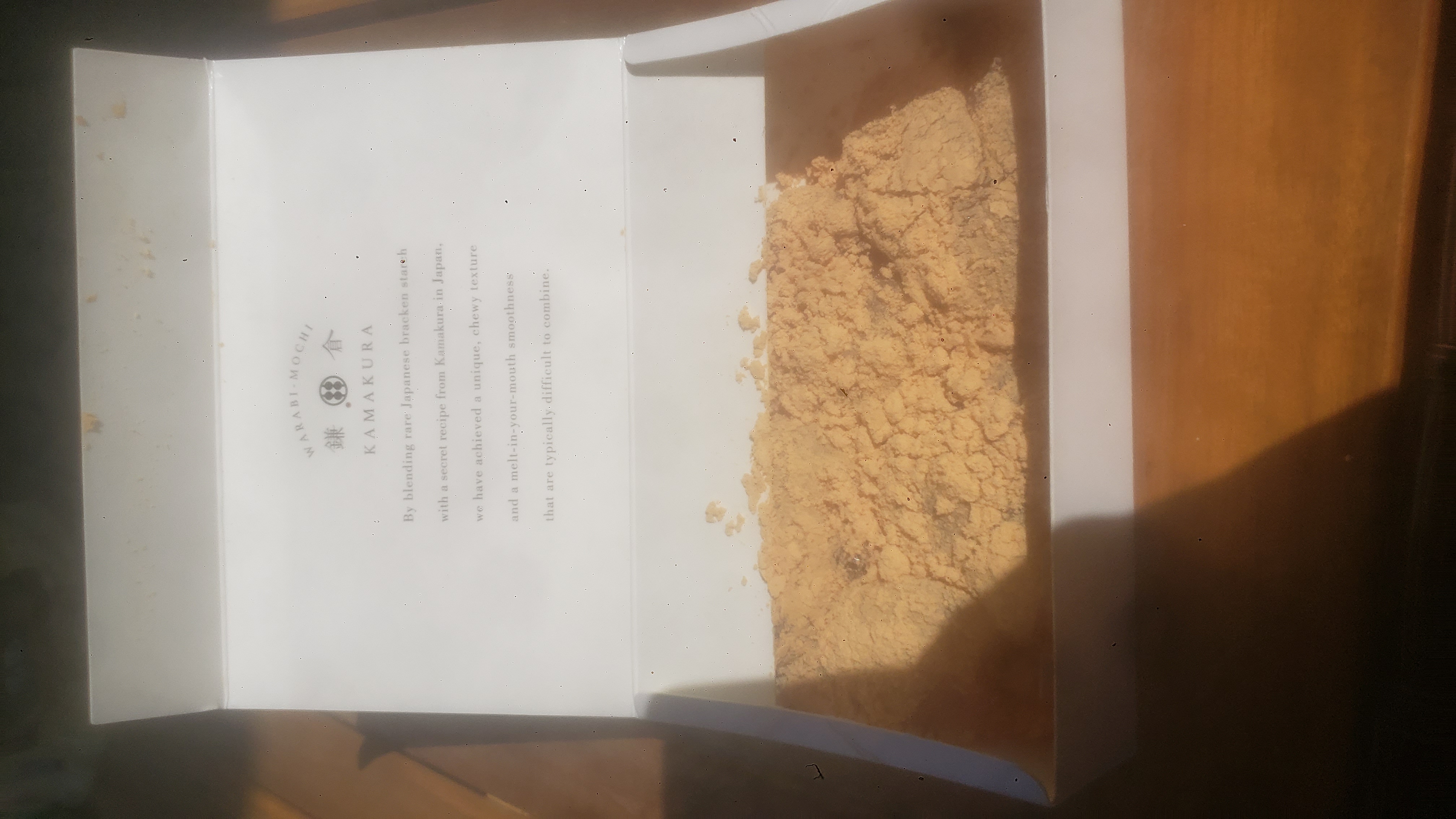 Warabi mochi dressed in soybean flour and brown sugar syurp in a to go box.